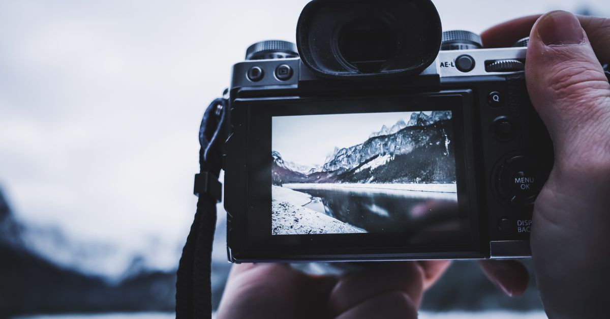 Persona fotografiando un paisaje de montaña con cámara en mano
